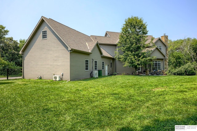 rear view of house featuring central air condition unit, a lawn, a shingled roof, and fence