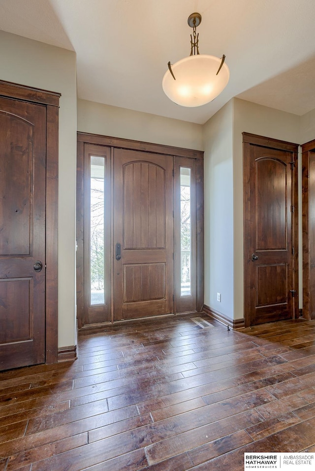 foyer entrance featuring dark wood-type flooring and baseboards