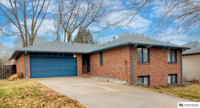 view of front of property with a garage, brick siding, concrete driveway, and fence