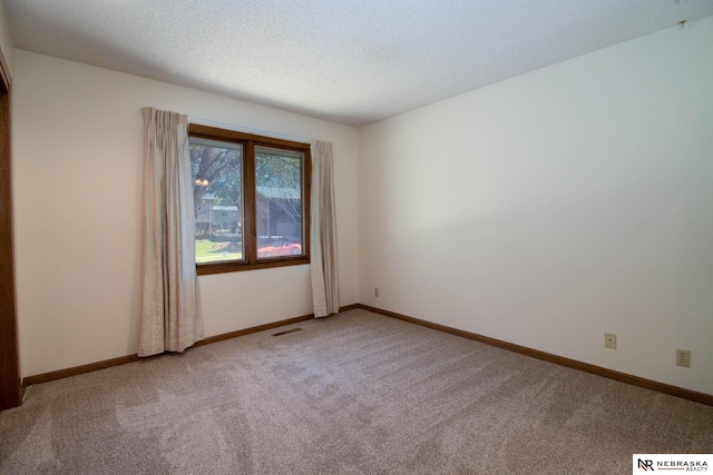 empty room featuring baseboards, carpet, visible vents, and a textured ceiling