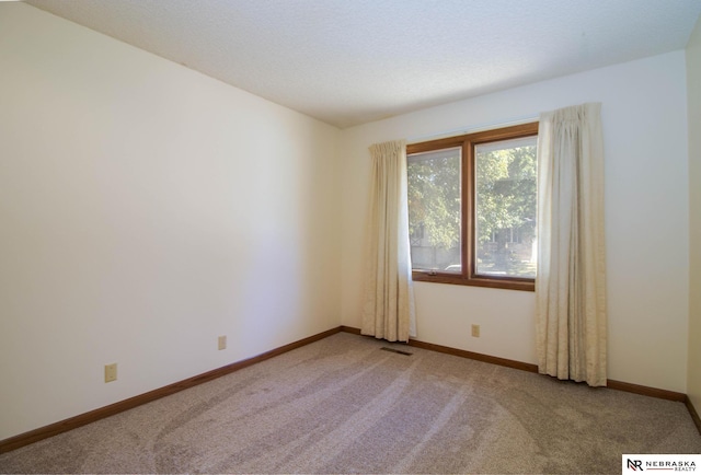 empty room with carpet flooring, visible vents, and baseboards