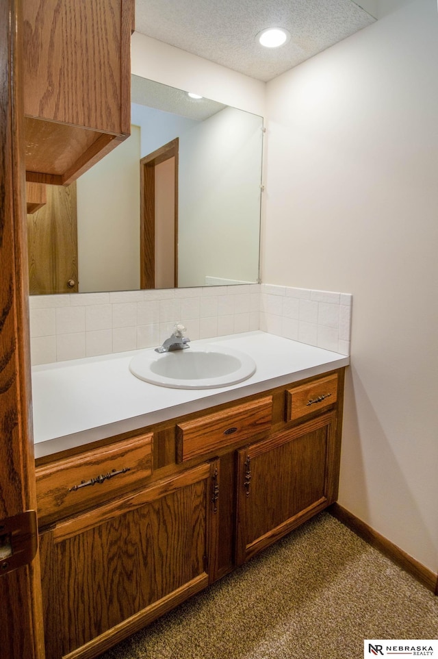 bathroom with baseboards, a textured ceiling, and vanity