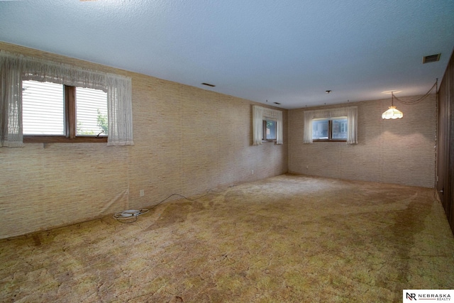 empty room with visible vents, brick wall, and carpet flooring