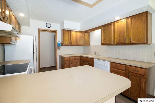 kitchen with tasteful backsplash, brown cabinets, light countertops, and white dishwasher