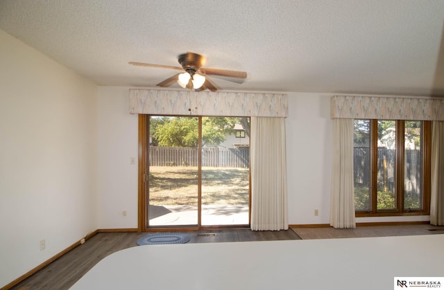 spare room with baseboards, a textured ceiling, a ceiling fan, and wood finished floors