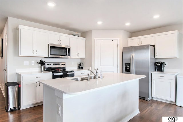 kitchen featuring light countertops, a kitchen island with sink, dark wood finished floors, stainless steel appliances, and a sink