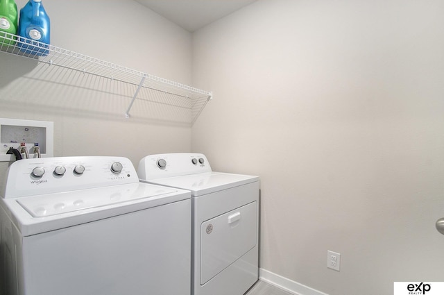 washroom featuring laundry area, baseboards, and washer and clothes dryer