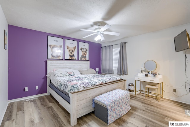 bedroom featuring baseboards, light wood-style floors, a ceiling fan, and a textured ceiling