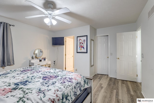 bedroom with visible vents, baseboards, light wood finished floors, and ceiling fan