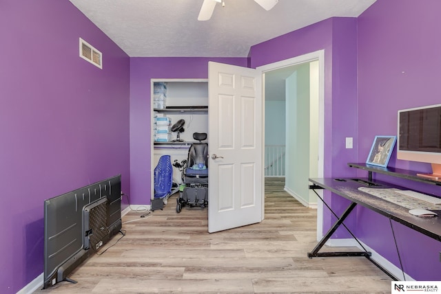 office area with visible vents, baseboards, ceiling fan, light wood-style floors, and a textured ceiling