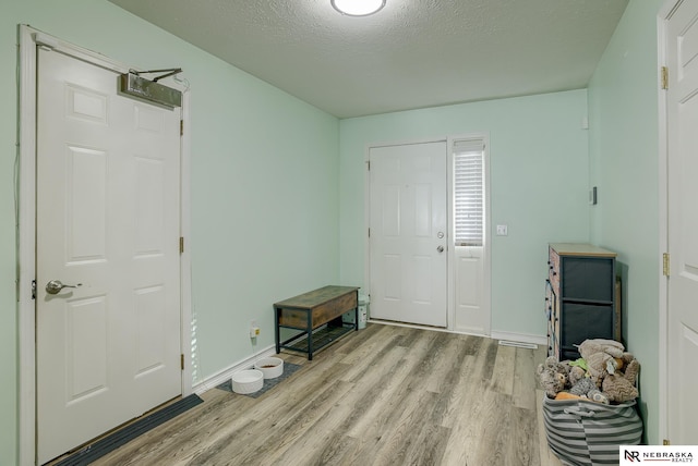 entryway featuring baseboards, a textured ceiling, and light wood finished floors