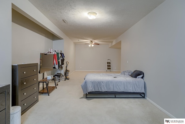 bedroom with light colored carpet, baseboards, and a textured ceiling