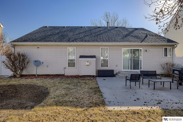 back of property with a yard, a shingled roof, and a patio