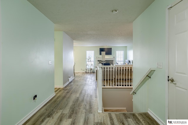 corridor with baseboards, a textured ceiling, and wood finished floors