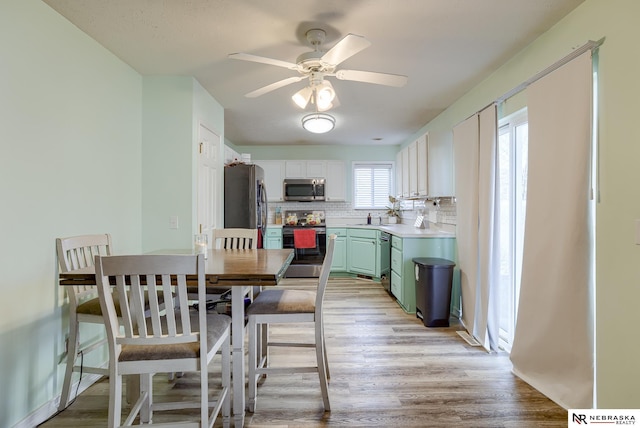 dining area with light wood finished floors and ceiling fan