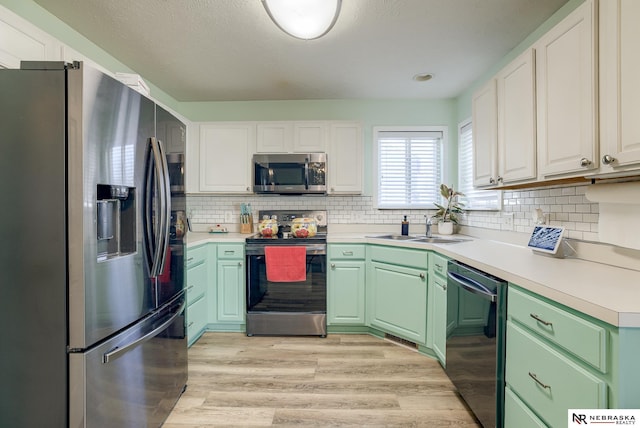 kitchen featuring light wood-style flooring, backsplash, appliances with stainless steel finishes, and a sink