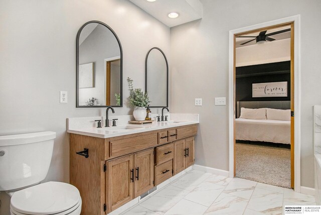 ensuite bathroom with toilet, baseboards, marble finish floor, and a sink