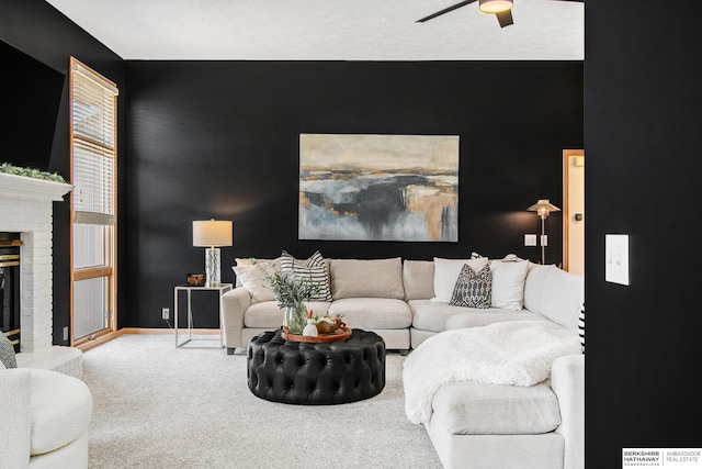 living area with a brick fireplace, baseboards, ceiling fan, and carpet floors