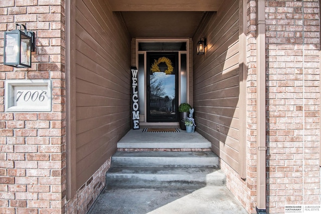 view of exterior entry featuring brick siding