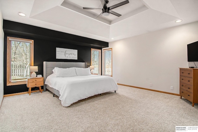 carpeted bedroom with recessed lighting, a tray ceiling, and baseboards