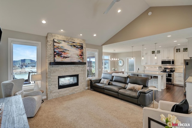 living room featuring recessed lighting, dark wood-type flooring, high vaulted ceiling, and a stone fireplace