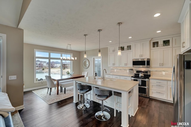 kitchen with dark wood-type flooring, a sink, stainless steel appliances, light countertops, and decorative backsplash