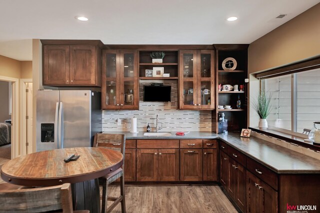 kitchen with tasteful backsplash, a sink, stainless steel fridge with ice dispenser, light wood-type flooring, and open shelves