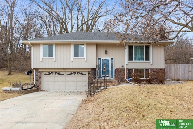 split foyer home featuring fence, driveway, an attached garage, a front lawn, and brick siding