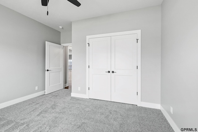 unfurnished bedroom featuring baseboards, ceiling fan, a closet, and carpet