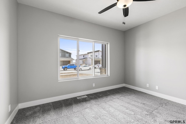 carpeted empty room with baseboards, visible vents, and a ceiling fan