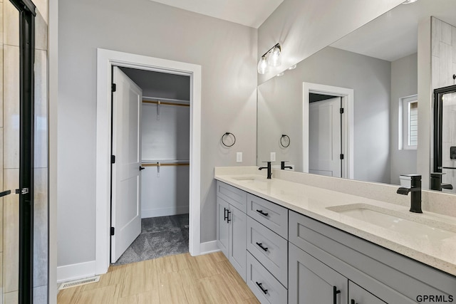 bathroom with double vanity, a spacious closet, visible vents, and a sink