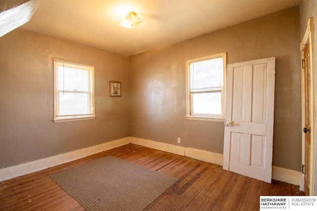 unfurnished room with hardwood / wood-style flooring and baseboards