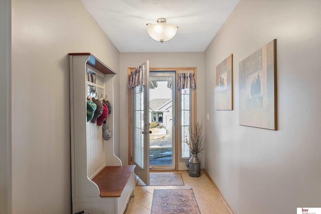 doorway featuring light tile patterned flooring and baseboards