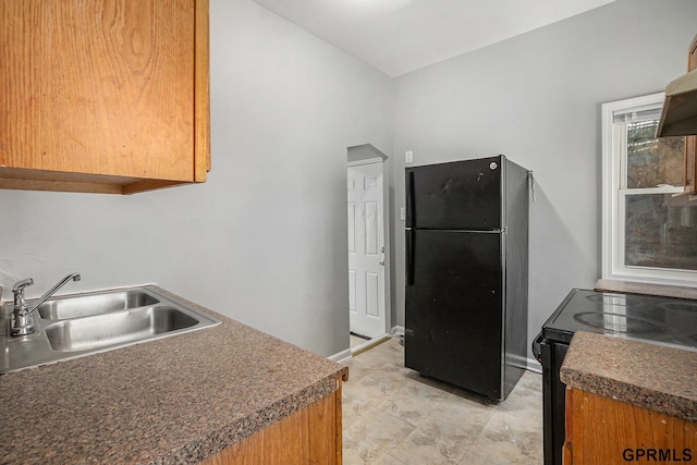 kitchen featuring vaulted ceiling, baseboards, a sink, and black appliances