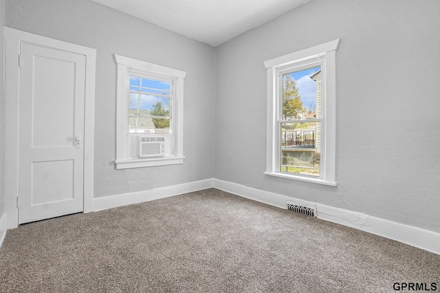 carpeted spare room with cooling unit, a wealth of natural light, baseboards, and visible vents