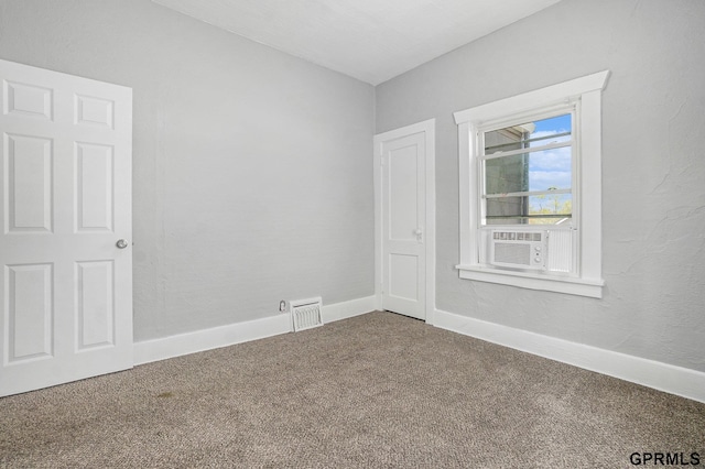 spare room with cooling unit, baseboards, visible vents, and carpet flooring