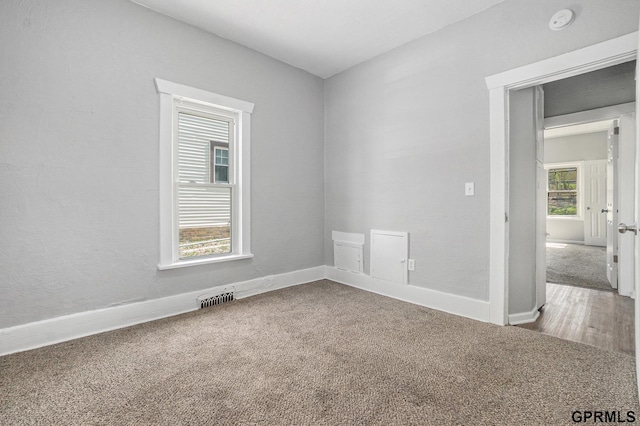 empty room with carpet floors, visible vents, and baseboards