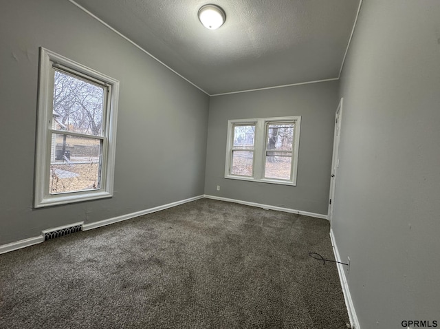 empty room with a healthy amount of sunlight, visible vents, and dark carpet