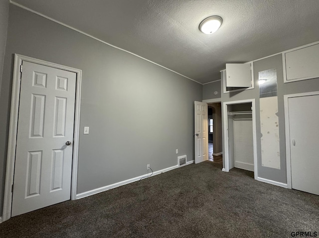 unfurnished bedroom with baseboards, visible vents, dark carpet, and a textured ceiling