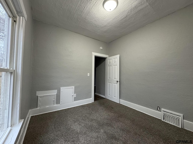 carpeted empty room with visible vents, baseboards, and a textured wall