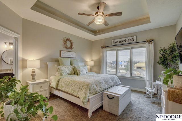 bedroom featuring baseboards, carpet floors, ensuite bath, ceiling fan, and a raised ceiling