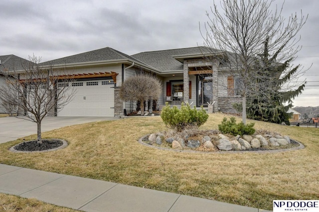 prairie-style home with stone siding, concrete driveway, a front lawn, and a garage