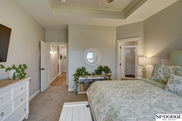 carpeted bedroom featuring a tray ceiling and baseboards