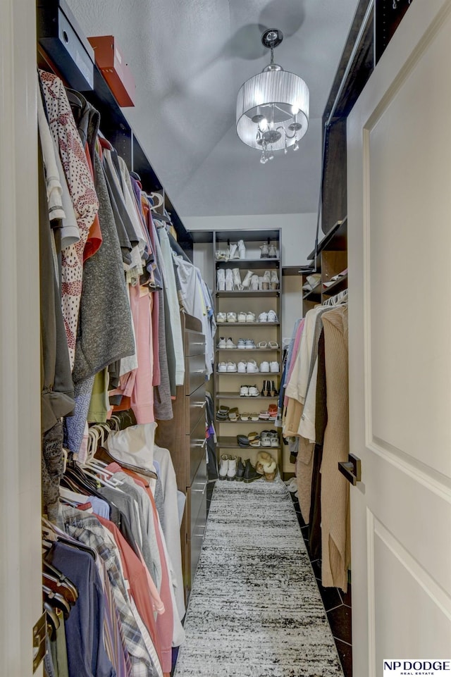 spacious closet with tile patterned floors and a notable chandelier