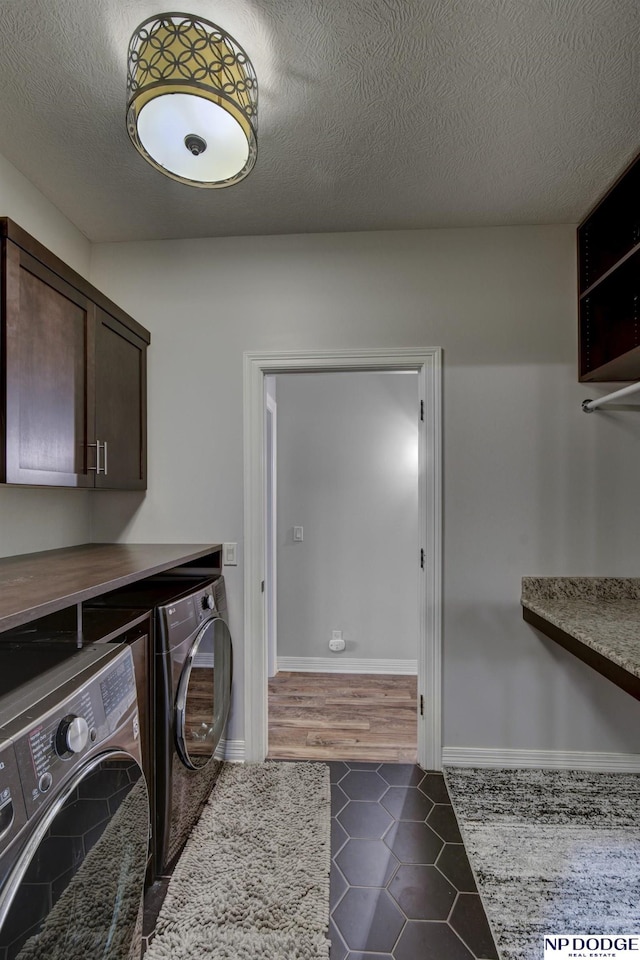 clothes washing area with dark tile patterned flooring, independent washer and dryer, a textured ceiling, cabinet space, and baseboards