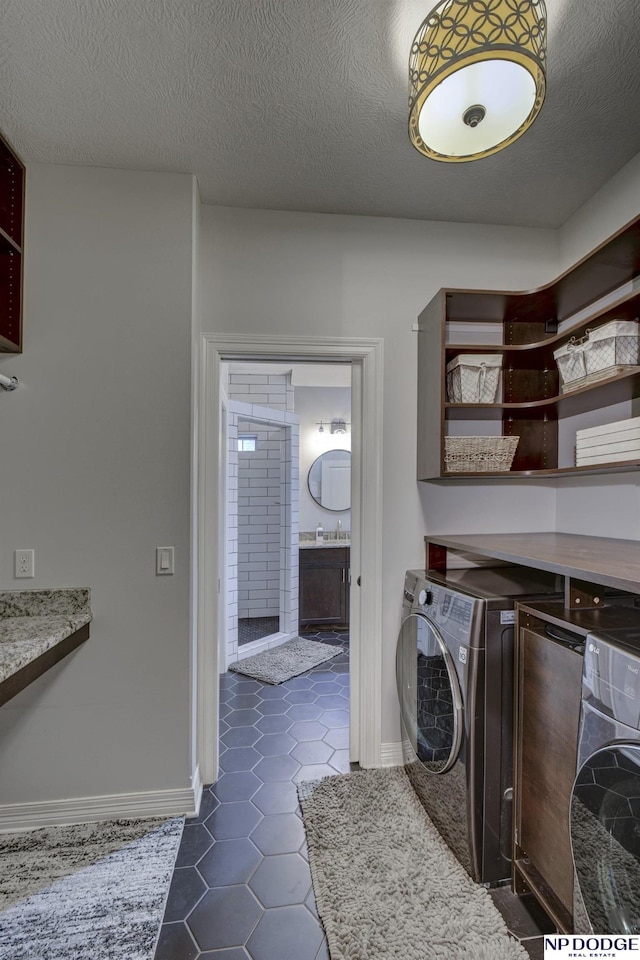 laundry area with laundry area, a textured ceiling, washer / clothes dryer, and dark tile patterned flooring