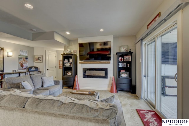 living area with a glass covered fireplace, light tile patterned flooring, and recessed lighting