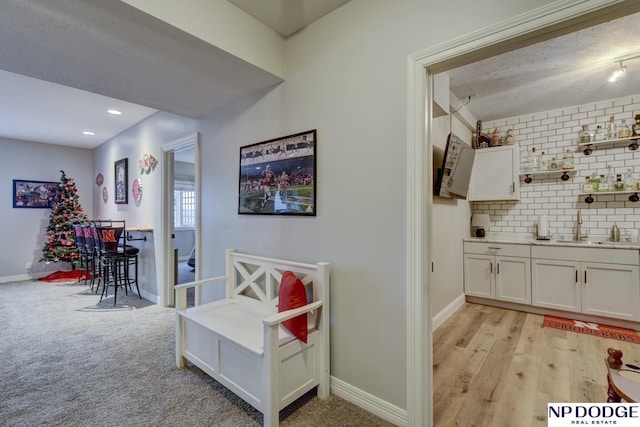 interior space with baseboards, light colored carpet, decorative backsplash, recessed lighting, and a sink