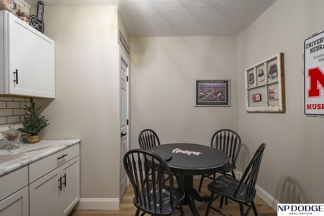 dining room with wood finished floors, baseboards, and a textured ceiling