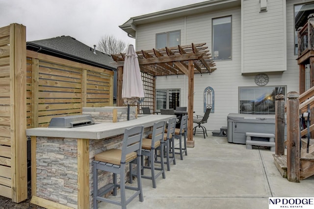 view of patio with area for grilling, a hot tub, outdoor wet bar, and a pergola